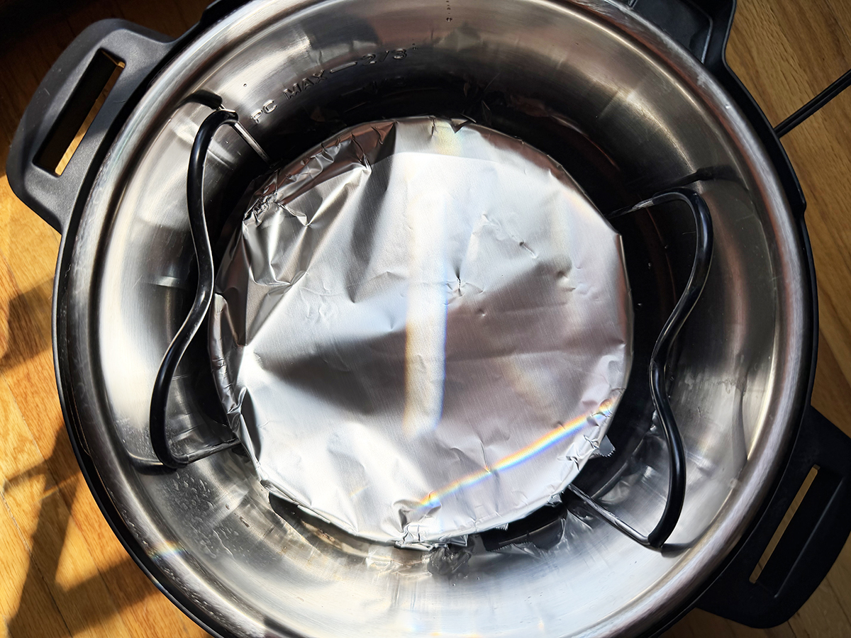 Pressure cooker with aluminum foil-lined insert for baking or steaming.