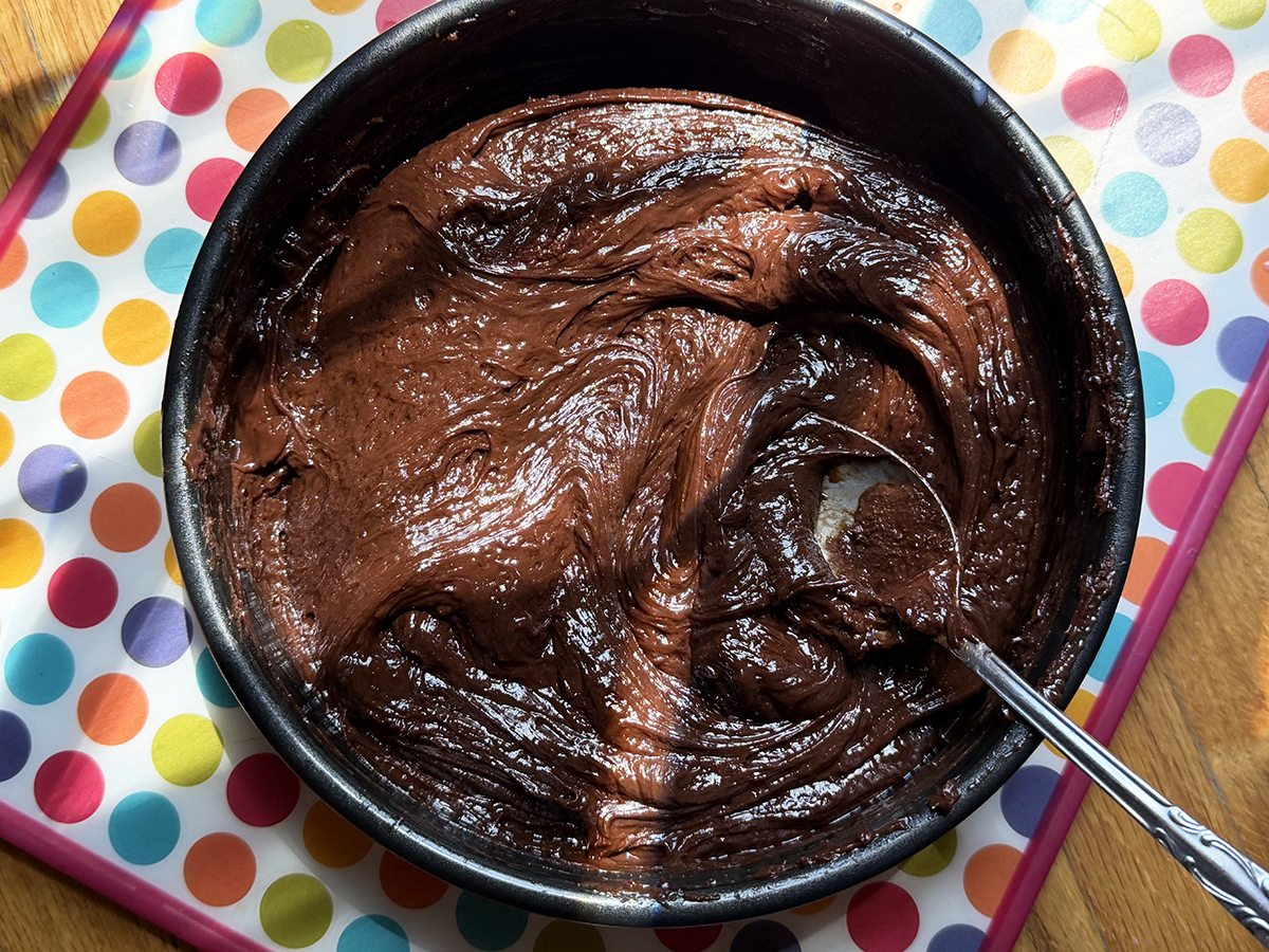 Rich, creamy chocolate fudge with a smooth texture in a black bowl. Perfect for dessert or sweet sna.