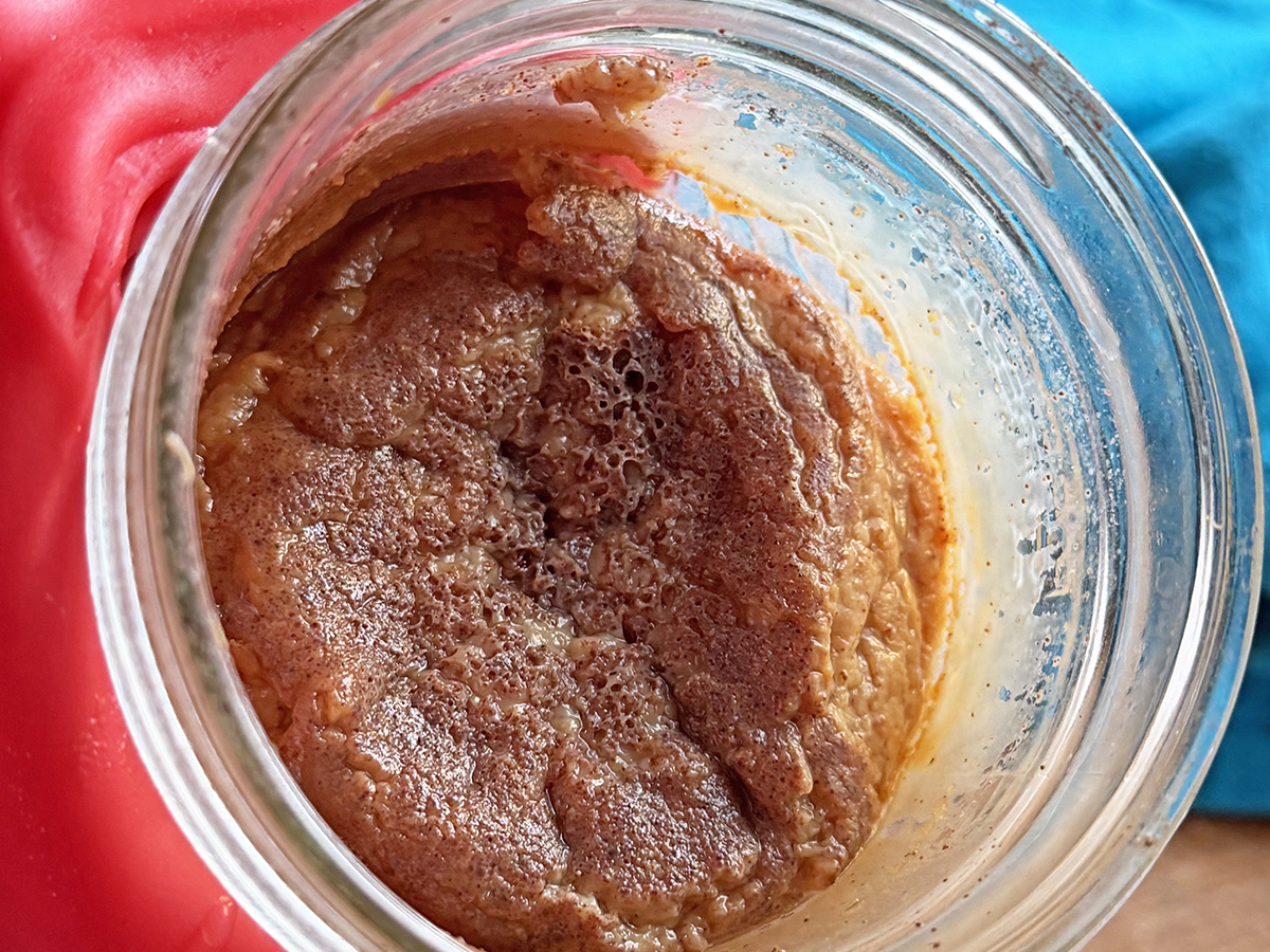 Close-up of chocolate cookie dough in a glass jar, ready for baking or snacking.