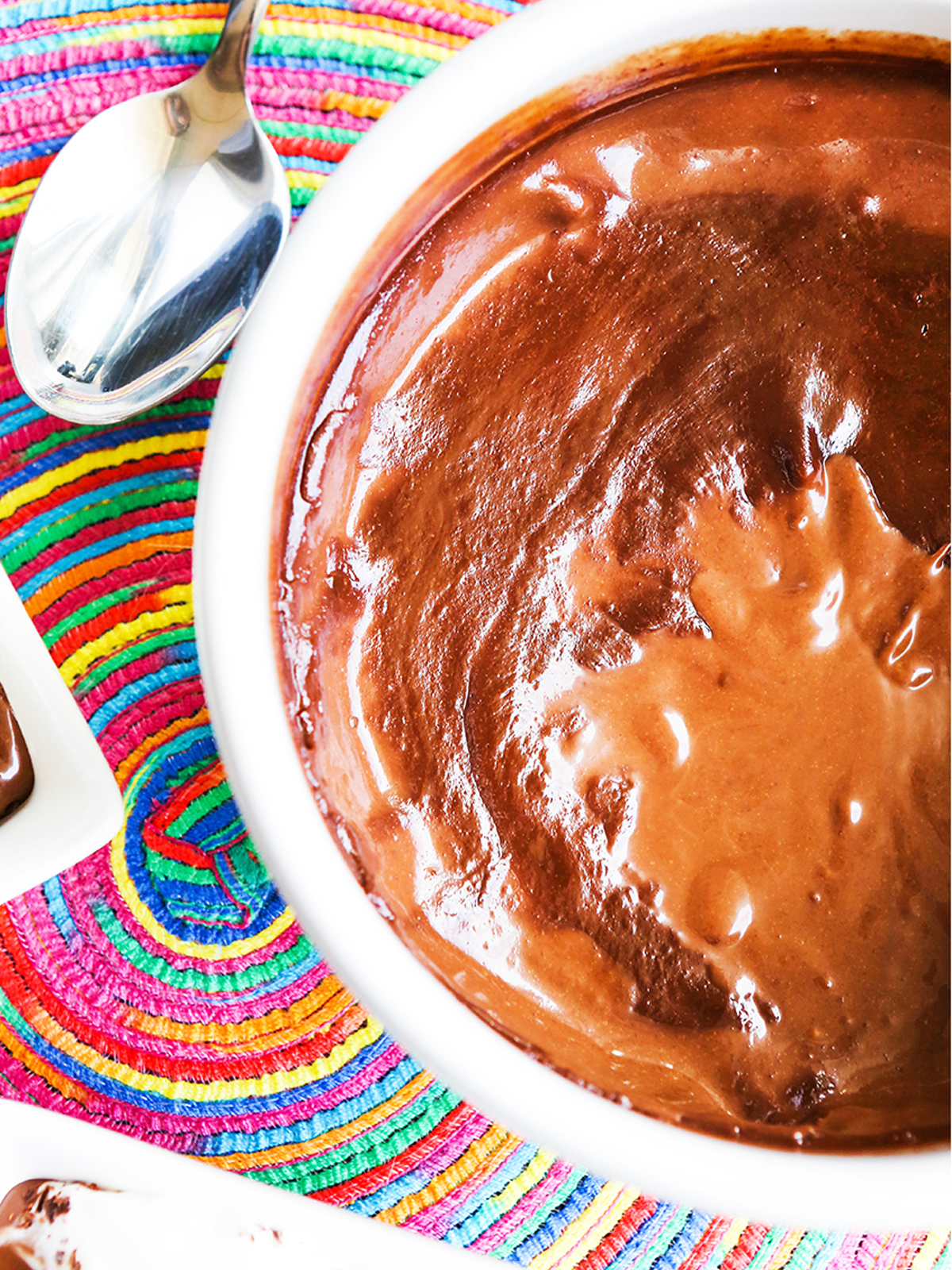Top view of a pan of chocolate pudding with swirls and a spoon next to it.
