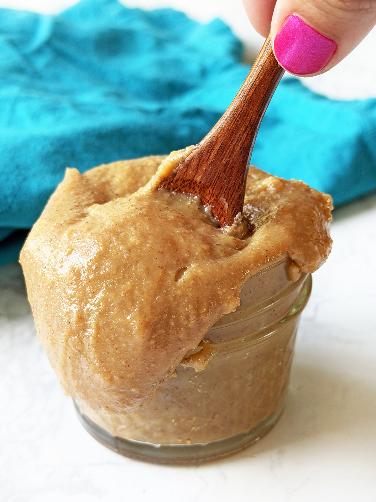 Creamy homemade peanut butter fudge in a glass jar with a wooden spoon.