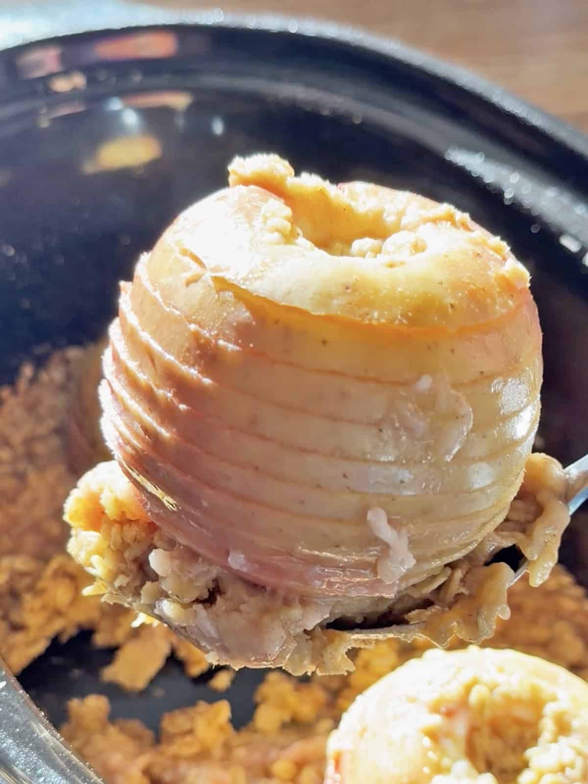 Spiral-cut whole apple in a crockpot with cooked filling around it.