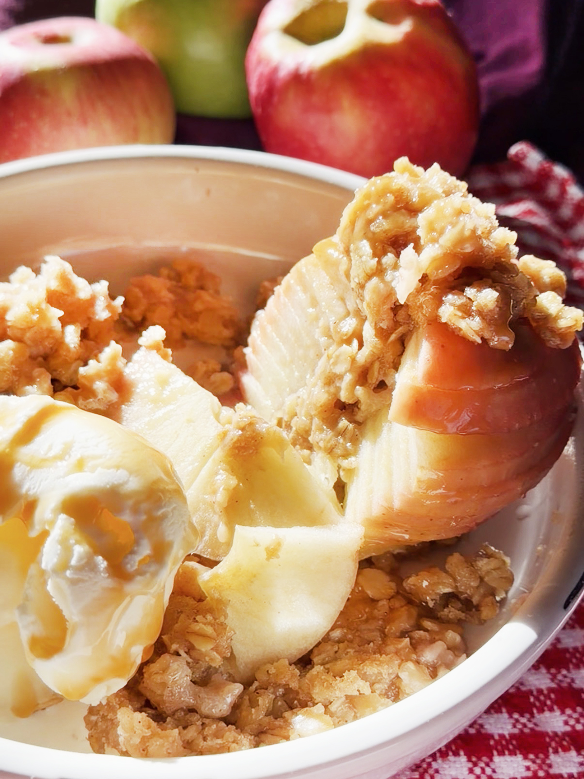 Spiral-cut apples with crumble topping and vanilla ice cream in a bowl.