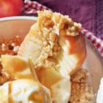 Baked apple with crumb topping and vanilla ice cream in a bowl.