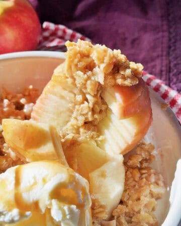 Baked apple with crumb topping and vanilla ice cream in a bowl.