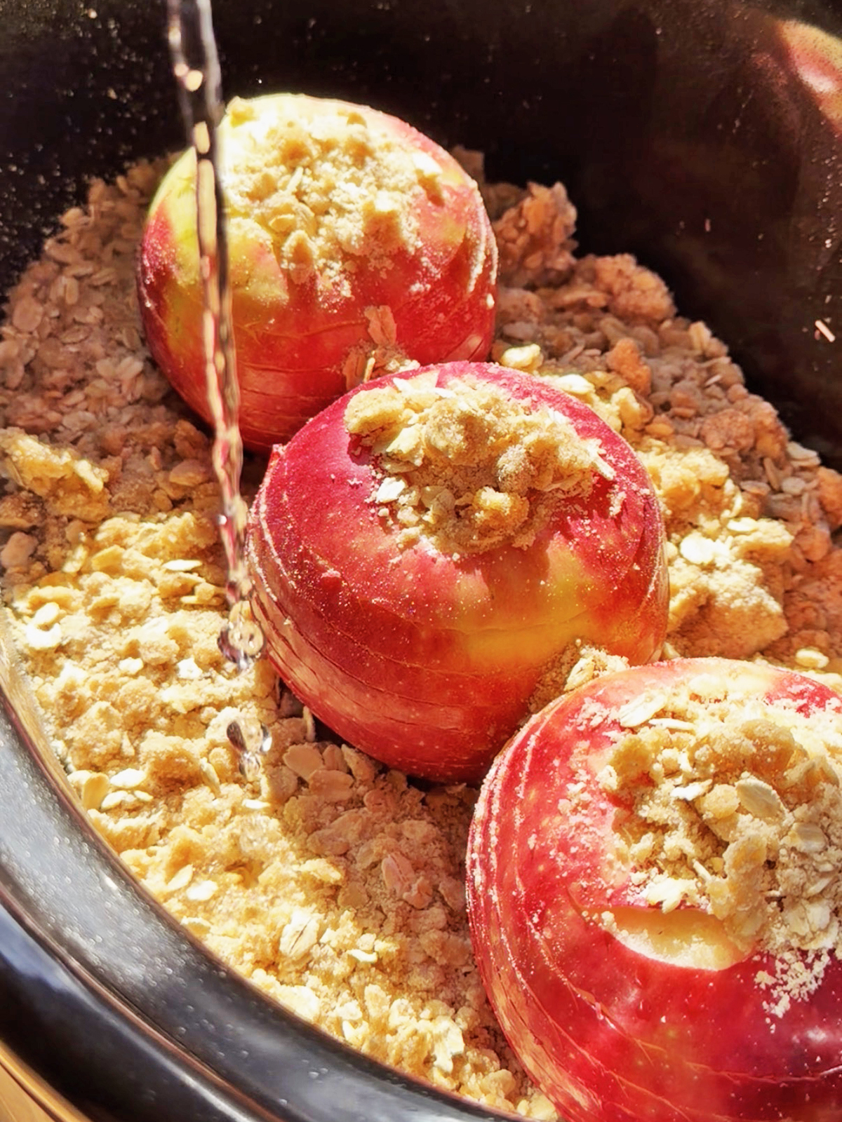 Spiral-cut whole apples in a slow cooker with crumb topping and apple filling.