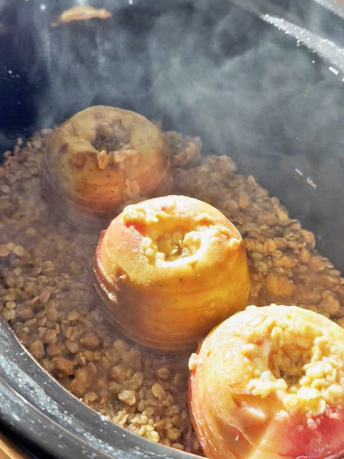 Spiral-cut apples cooking in a slow cooker with brown sugar and spices.