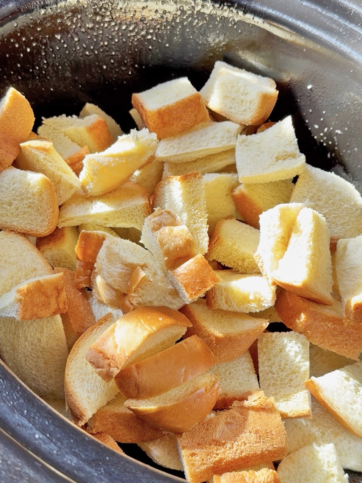 Cubed bread and apple slices in a slow cooker for French toast.