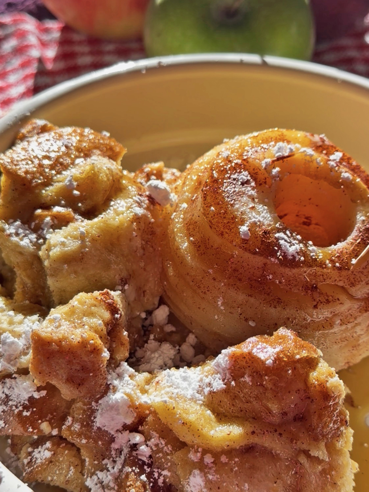 Baked apple slices with cinnamon and powdered sugar in a bowl.