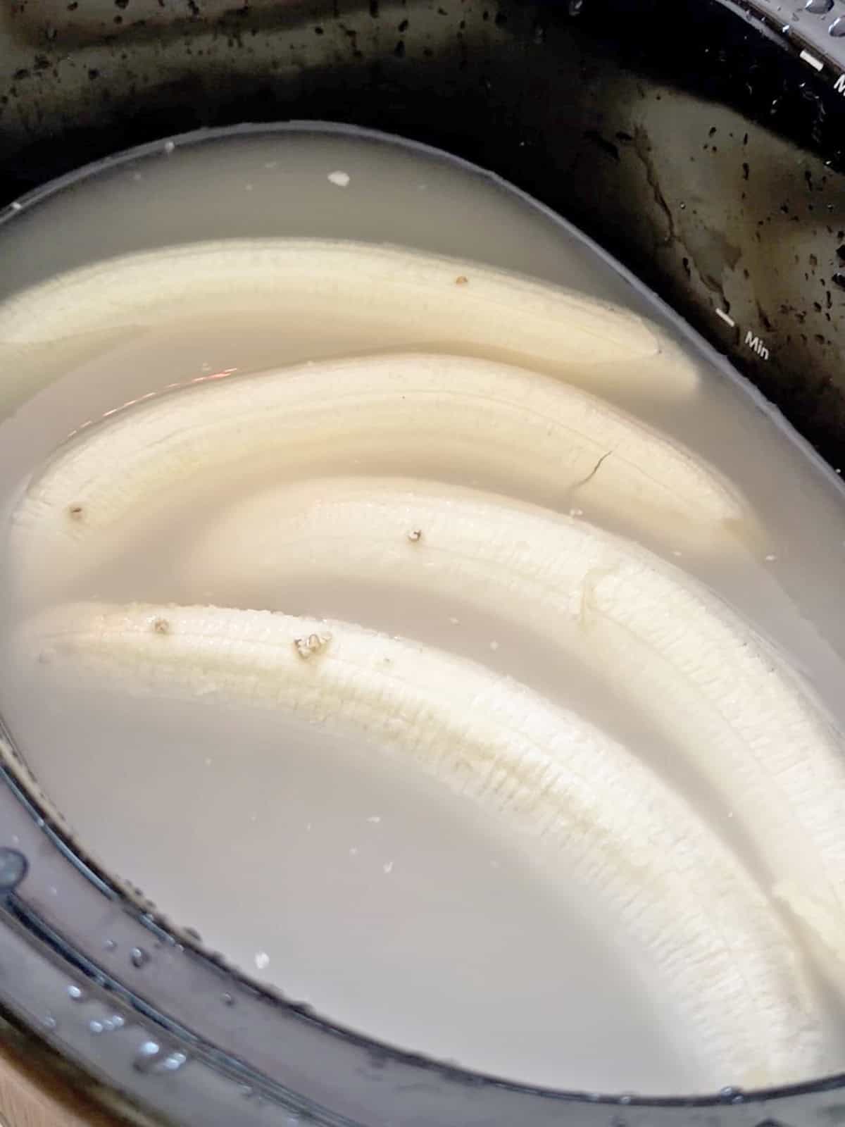 Sliced bananas in a creamy mixture in a slow cooker for oatmeal.