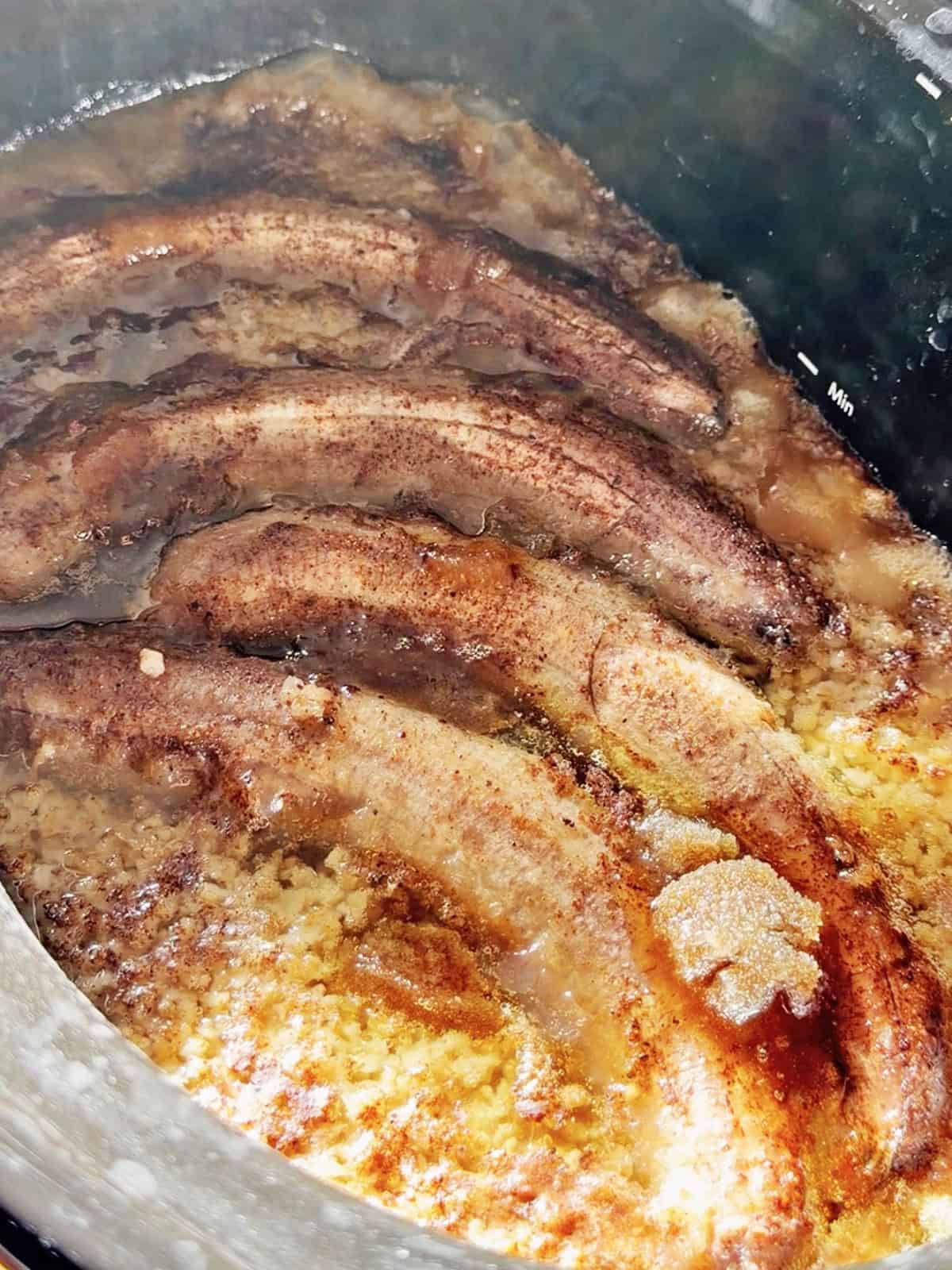 Bacon strips in a skillet with crispy edges and rendered fat.
