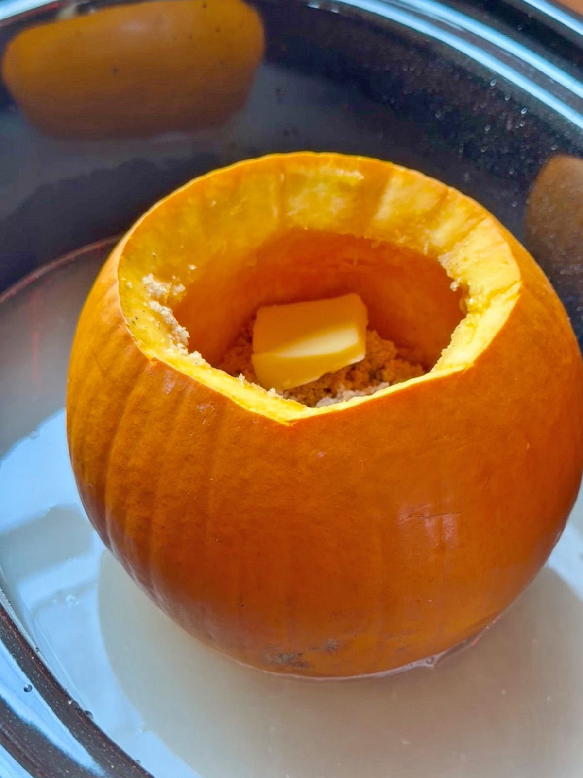 Pumpkin with a butter piece inside, ready for cooking in a slow cooker.