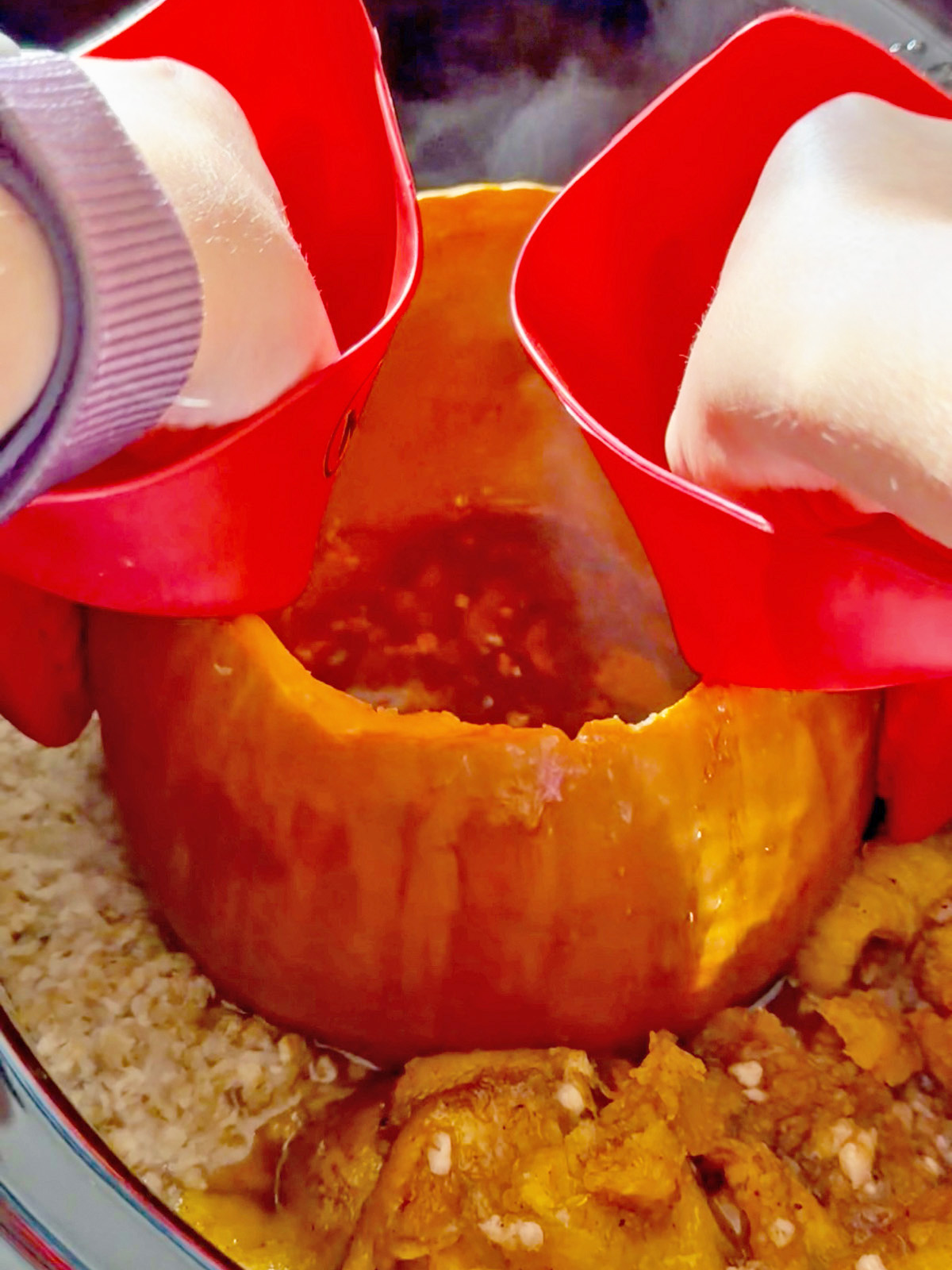 Pouring milk into a pumpkin-shaped bowl of oatmeal with pumpkin pieces.