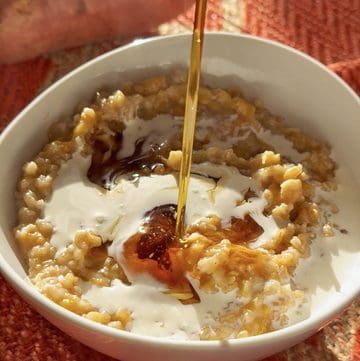 Creamy oats with yogurt, maple drizzle, and crushed nuts in a white bowl.