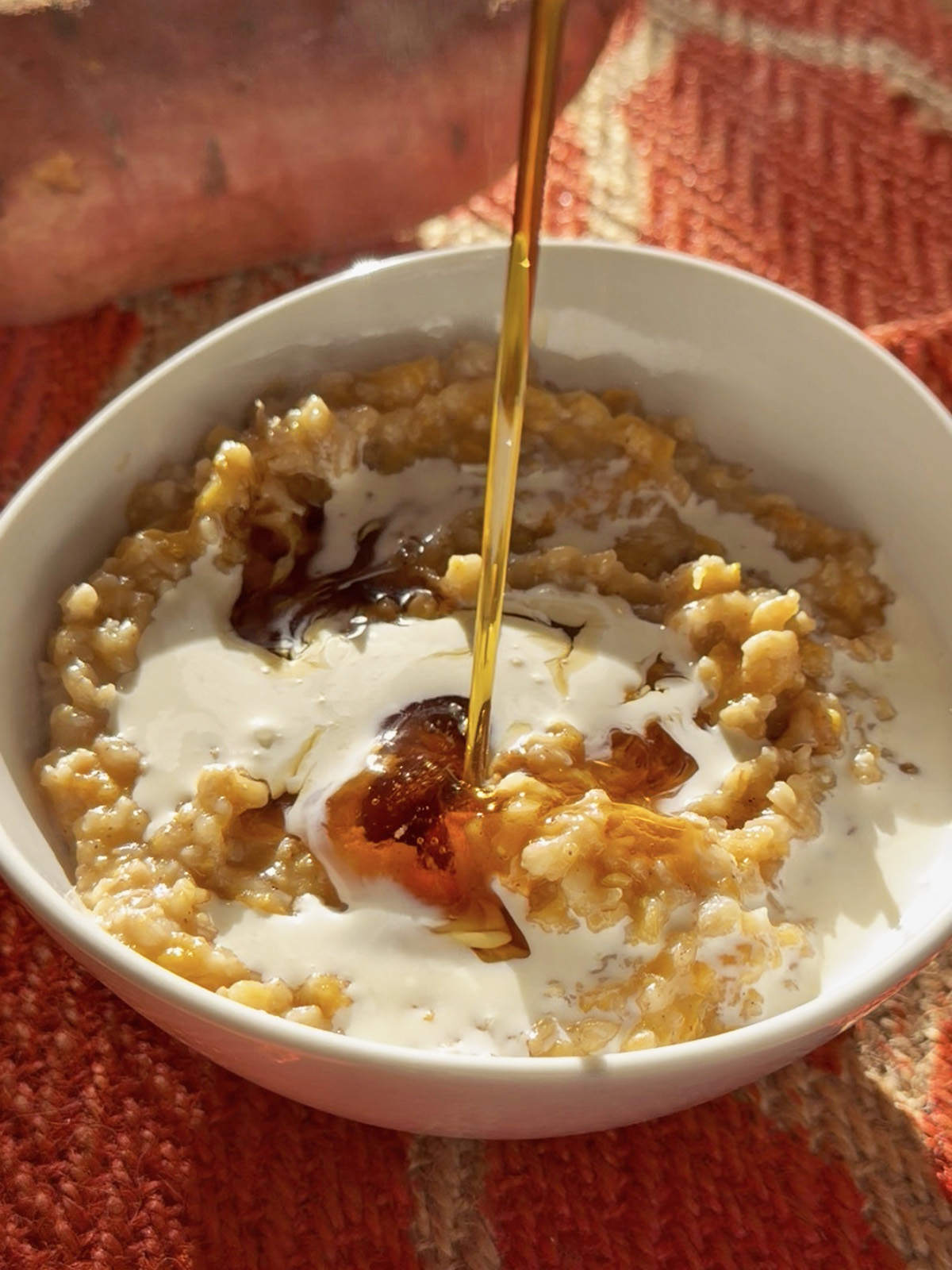 Creamy oats with yogurt, maple drizzle, and crushed nuts in a white bowl.
