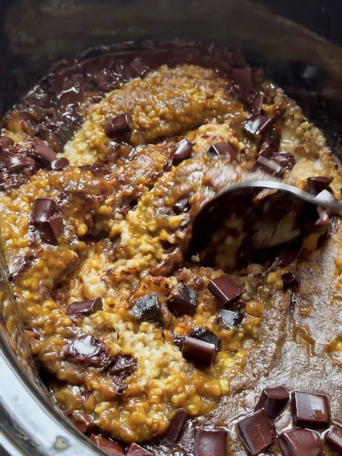 Creamy pumpkin oats with melted chocolate chunks in a crockpot.