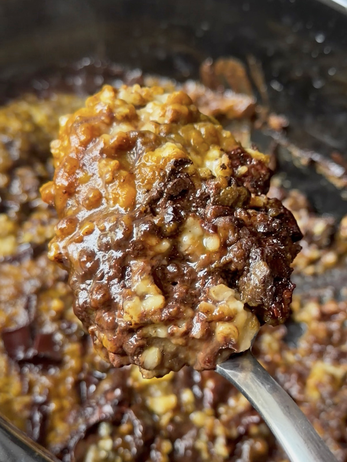 Hearty spoonful of pumpkin chocolate oatmeal with melted chocolate chips and nuts.