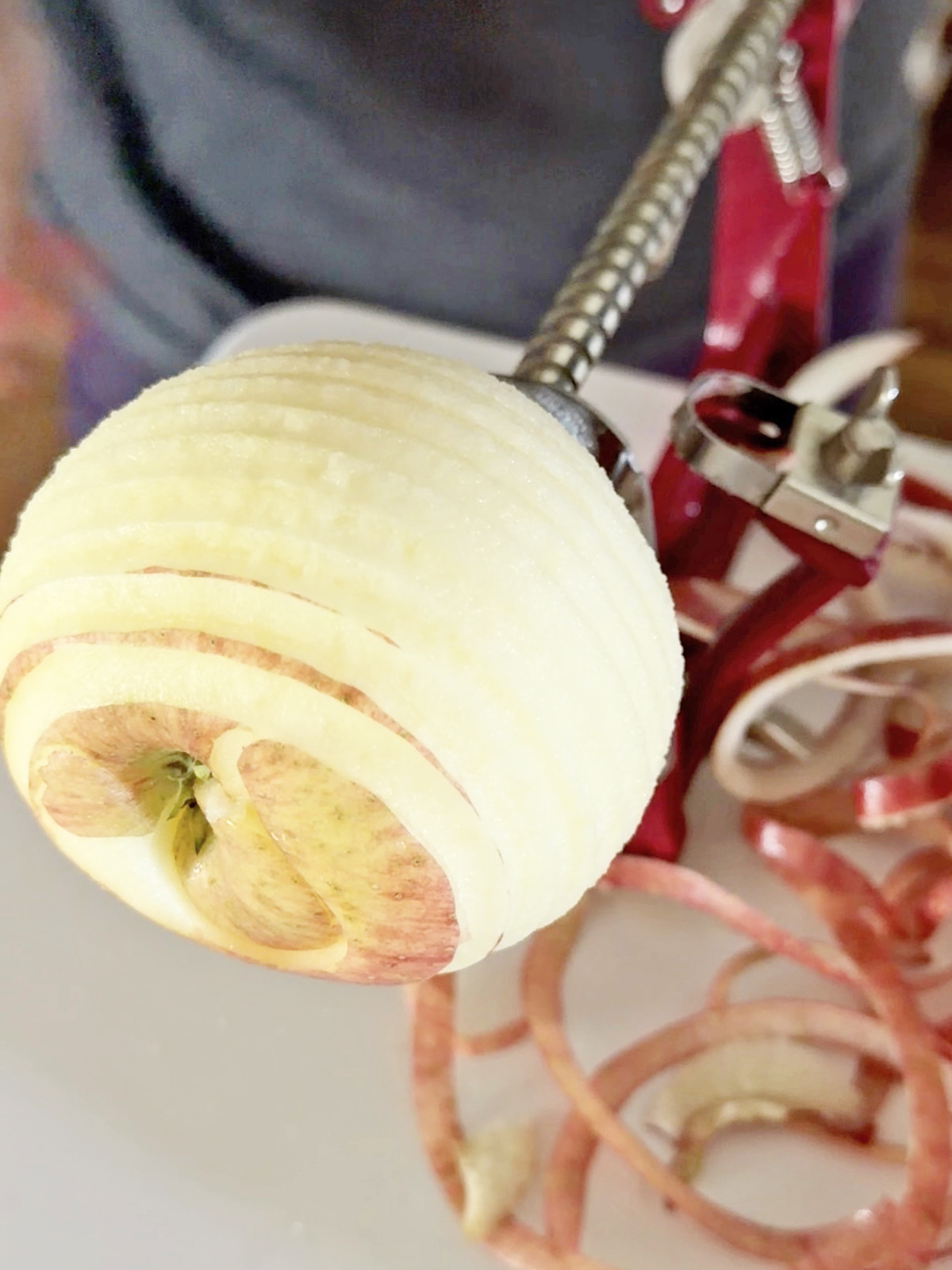 Sliced apple on a skewer with onion rings in the background.